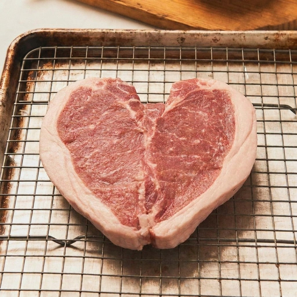 Raw boneless Mangalitsa butterfly pork chop opened flat, marbled meat with a creamy fat cap